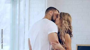 Happy young couple gently kiss each other on the lips and tight hug.