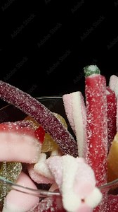 I take a twisted pink gummy candy stick dusted with sugar from the glass of gummy candies. Dolly slider extreme close-up.