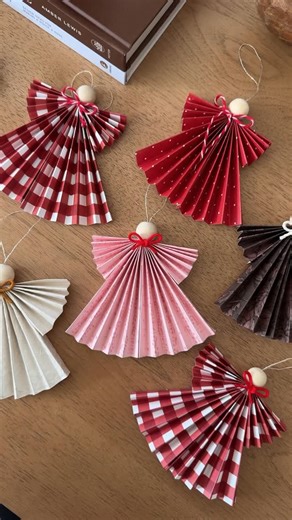 Deborah Trette on Instagram: "diy paper angels as the prettiest gift toppers or ornaments! such a good craft to try right before the holidays too! You’ll need: festive paper string/yarn hot glue wooden beads cut paper into squares and fold accordion style (2). Fold 1/3 in making the wing and hot glue. repeat this step folding the opposite side. add a yarn or string loop before hot gluing two pieces together. hot glue the wooden bead. #christmasdiy #christmascraft #giftidea #giftwrap"