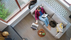 Overhead view of woman writing notes, lying on couch at home