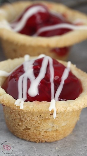 Cherry Pie Cookie Cups taste like mini cherry pies with a sugar cookie crust! This is an easy recipe you can make with four ingredients. The cookie cups are filled with cherry pie filling and topped with a simple glaze. Full recipe here: https://www.crazyforcrust.com/cherry-pie-cookie-cups-recipe/ | CrazyforCrust