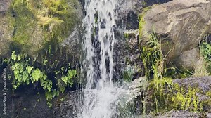 Cinematic close-up booming down shot of a fast-moving waterfall on the Waimea Canyon Lookout Trail in Kaua'i, Hawai'i. 4K HDR at 30 FPS