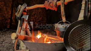 roasting meat on a stick while baking bread in a dutch oven on a campfire
