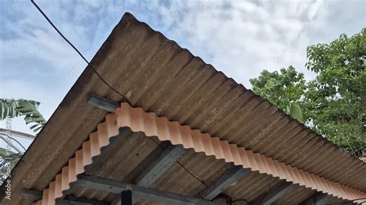 Detail of the wave roof with light asbestos frame and decorative lisplang under cloudy skies.