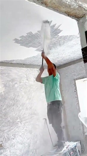 Construction worker using scraper tool to remove ceiling plaster