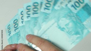 Brazilian currency, 100 Reais banknotes folded and counted in your hands