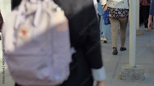 Female commuters walk on the rail-side platform of a commuterline electric train at a station during the daytime.