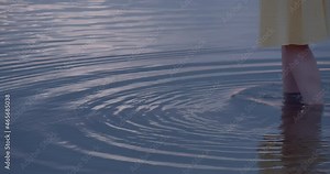 Barefoot female with yellow summer dress walking into calm sea water