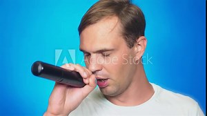 a crazy funny young man sings songs into a microphone. color background, close-up. 4k, slow motion