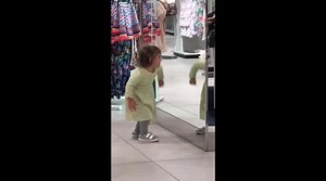 Cute girl dancing to her own reflection in front of the mirror