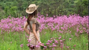 Adventure and wildlife exploration in Africa. Serengeti National Park. Cheerful woman exploring a tropical jungle. stylish woman in safari clothes stands in the savanna among purple flowers