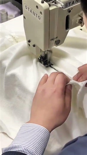 stitching white fabric material using an industrial sewing machine for professional garment clothes