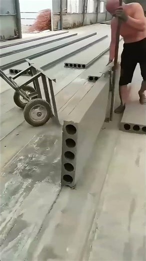 Worker Uses Long Rod to Move Large Precast Concrete Panels in Factory
