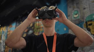 The guy puts a helmet on his head to control the drone.He holds on to his helmet with his hands