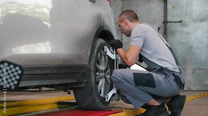 A car service employee installs a wheel adapter with a target on the wheel to perform a wheel alignment. Diagnostics and balancing.