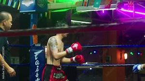 4K Cinematic slow motion footage of two Thai fighters fighting on a boxing ring during a Muay Thai boxing fight in a stadium in Chiang Mai, Thailand
