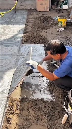 Laying large ceramic floor tile onto wet cement base mixture