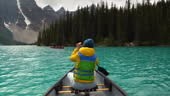 Female tourist paddling a canoe on Moraine Lake during summer in...