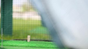 Man is taking a mashine and hitting the ball for golf.