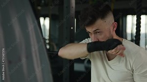 Close up Caucasian man boxer box training in dark gym fitness club sweaty motivated male sportsman fighter boxing training fist strikes punches beating punching bag professional sport workout fight