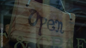 Open sign crafted with handwritten font on wooden board in window