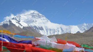SLOW MOTION, CLOSE UP DOF: Colorful flags flutter in front of windswept Everest in the distance. Winds blowing across Mount Everest Base Camp sweep ice and snow off the mountaintop and make flags flap