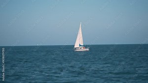 a slow-motion, cinematic shot of a sailboat gracefully gliding on a calm sea during sunset. The sailboat, with its tall mast and sleek white hull, stands out against the tranquil waters. The horizon