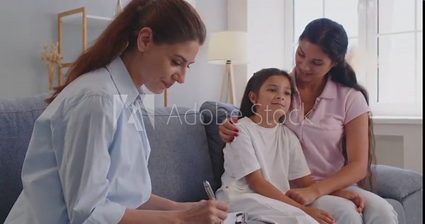 Family psychologist conducts a consultation and examination at home, making notes, how the mother calms her daughter during the visit. Psychological support and child mental health.