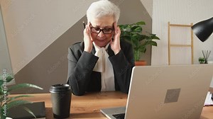 Middle aged senior woman touching temples experiencing stress in office. Older mature leader boss tired of working feeling headache sick. Long laptop usage computer vision syndrome. Office syndrome