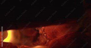 Log burner with macro logs on fire with glowing embers and dancing flame. Filmed in slow motion.