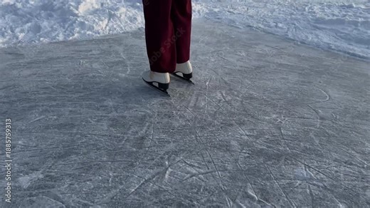 Close-up of woman ice skating on frozen lakewhite figure skates on frozen ice rink surface with scratch marks and patterns from skating blades