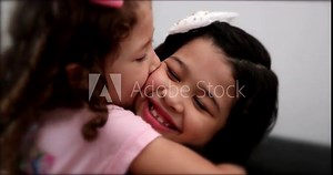 Cute mix race little sisters kissing each other. Children siblings love and affection