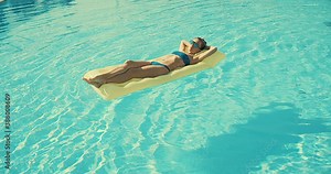 Woman sunbathes in the pool, swimming on the air mattress in hot summer day. Relax, Travel, Holidays, Freedom concept. 4K slow motion