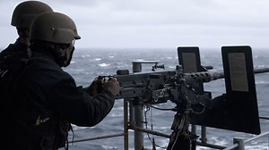 US Navy sailors fire heavy machine gun on aircraft carrier