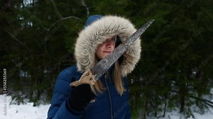 Woman with a saw looking for a christmas tree to cut and take home