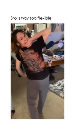 Brutal Humors on Instagram: "This video captures a moment of impressive agility as a person performs an athletic floor stunt in a domestic setting. ​The Subject ​A person with long brown hair, wearing a black graphic t-shirt and grey joggers, is centered in a room that appears to be a bedroom or apartment. The space is lived-in, featuring a wooden bed frame cluttered with various items, a couch, and a glimpse of a kitchen in the background. ​The Mechanism ​The person begins on the floor, arching