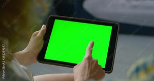Woman using tablet computer, watching green screen on mobile device, chroma key, touching a screen, enjoying online entertainment at home, close up, 4K, shot on RED camera