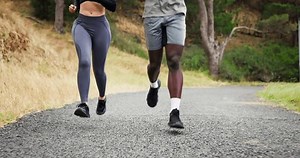 People, running and legs on mountain road or exercise, healthy and nature for marathon training or practice. Athlete, feet and race on forest hill or together as wellness goals, cardio or sport