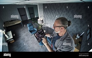 Male mature technician adjusts angle of CCTV camera, uses tablet computer with displayed security cameras video footage on screen. View from surveillance camera. Monitoring and tracking. CCTV system Stock Photo - Alamy