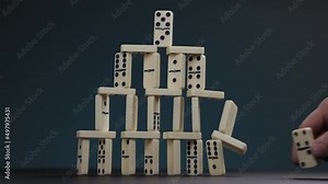 Falling dominoes. Chain reaction, built figure of dominoes falling in slow motion. Domino house.