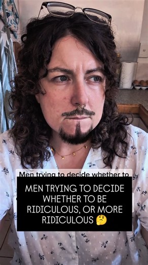 Sarah on Instagram: "It's so hard to choose 😩 ***VIDEO TRANSCRIPT*** (A white woman in her 30's with shoulder-length dark, curly hair and a goatee filter, sitting in a kitchen wearing a white buttoned shirt with a blue floral print, a gold necklace with butterfly charms, and a gold nose ring.) TEXT READS: Men trying to decide whether to spend their day lecturing women online about accountability, or recording a podcast about how it's women's fault that men might shoot up a school if they don't