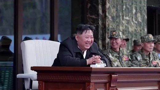 Smiling Kim Jong Un watches special forces troops hit each other with bricks and axes in military parade