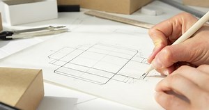 clip-1069788979-designer-draws-mockup-crafting-eco-cardboard-box