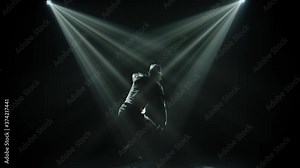 Dark silhouette guy dancing in a street style break dance. Black background with neon spotlights and lots of smoke. Slow motion.