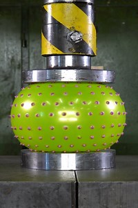Hydraulic press crushing spiky stress ball
