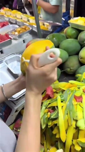 peeling fresh yellow organic mango manually using special tool