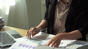 Young female accountant working on documents in the office, financial calculations, using a calculator, reading documents while working on accounting and analyzing financial budgets in the office.