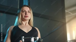 Medium shot of fit blonde performing exercises on cable crossover machine. Woman performs cable row, pulling handle towards chest with both arms. High quality 4k footage