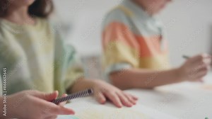 Medium tilt of two Caucasian preschool children quietly sitting at table in kindergarten neatly drawing using wax crayons and colour pensils during art class