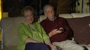Elderly couple watching TV changing channels with remote